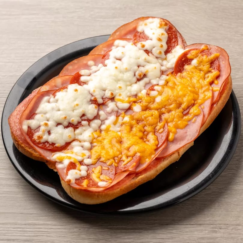 Pizza Shoppe's toasted sub with pepperoni, ham, melted mozzarella, and cheddar cheese on a black plate.