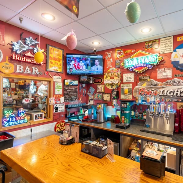 A vibrant bar area with neon signs, a TV, and beer taps, reflecting a lively atmosphere.