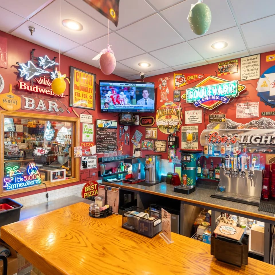 A vibrant bar area with neon signs, a TV, and beer taps, reflecting a lively atmosphere.