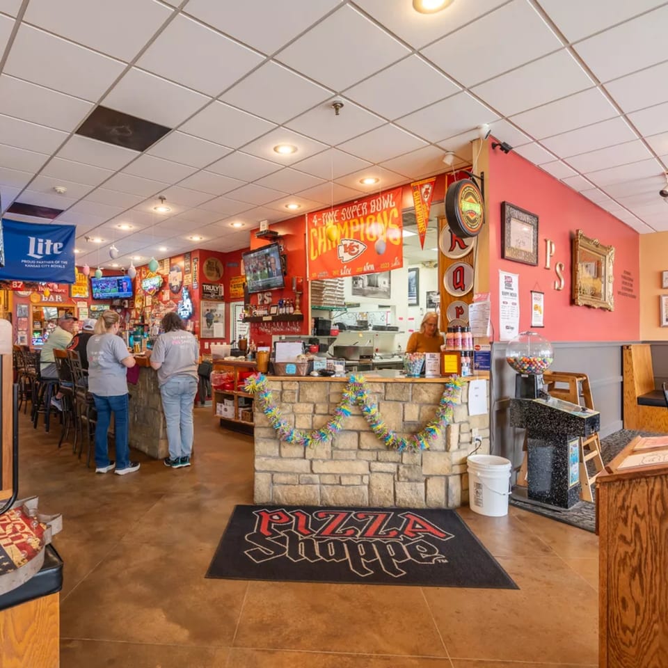 Interior of Pizza Shoppe with a bar, counter, and Kansas City Chiefs decorations.