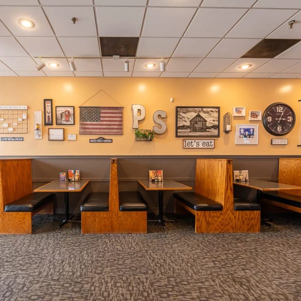 Cozy Pizza Shoppe dining area with wooden booths, tables, and Americana-themed wall decor.