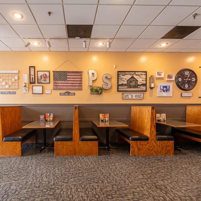 Cozy Pizza Shoppe dining area with wooden booths, tables, and Americana-themed wall decor.